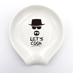 a white plate with a man's hat and glasses on it that says let's cook