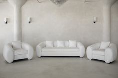 three white couches in an empty room with chandelier hanging from the ceiling