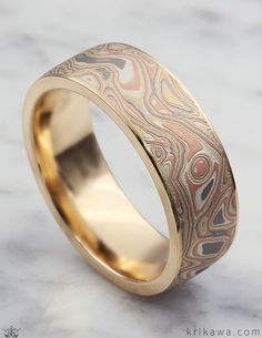 a wedding ring with gold and silver inlayed to the surface on a marble background