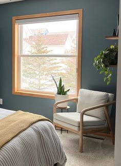 a bed room with a neatly made bed and a chair next to a large window