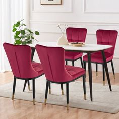 a dining room table with red chairs and a white rug on top of the floor