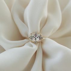 a close up view of a ring on a white satin fabric with diamonds in the center