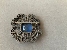 Beautiful blue stone brings brilliance to this old brooch. It measures 1.75 inches in width and length. Antique, and so pretty. Great gift for Mother's Day! Formal Blue Gemstone Brooch, Formal Blue Gemstone Brooches, Vintage Gemstone Brooches For Formal Occasions, Antique Blue Jewelry With Brooch, Blue Gemstone Brooch For Anniversary, Blue Gemstone Brooches For Anniversary, Blue Cabochon Brooch For Formal Occasions, Formal Blue Cabochon Brooch, Elegant Blue Gemstone Brooch