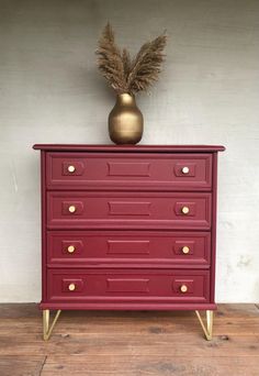 a red dresser with gold handles and drawers