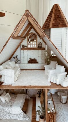 a doll house made out of wood with white furniture and pillows on the bottom floor