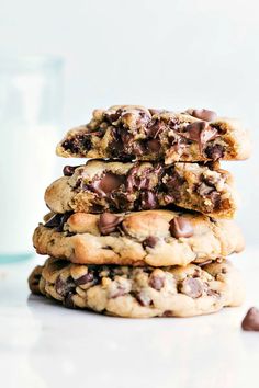 chocolate chip cookies stacked on top of each other with a glass of milk in the background