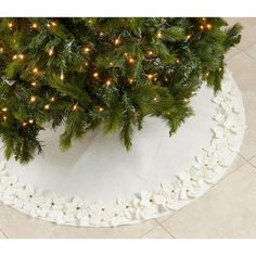 a christmas tree skirt is on the floor next to a potted plant and white flowers