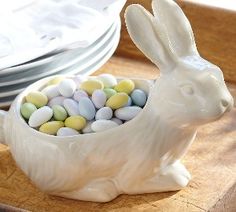 a white bunny sitting in a bowl filled with candy