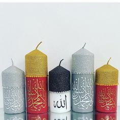 four different colored candles with arabic writing on them