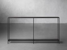 a black metal and glass console table against a gray wall with no one in it