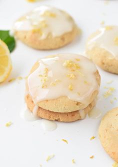 lemon cookies with icing and sprinkles on a white surface next to sliced lemons