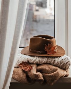 a hat and sweaters are sitting on a window sill