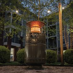 an outdoor fire pit sitting in the middle of a park at night with lights on