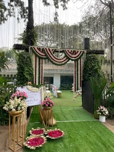 an outdoor ceremony setup with flowers and greenery on the grass in front of it