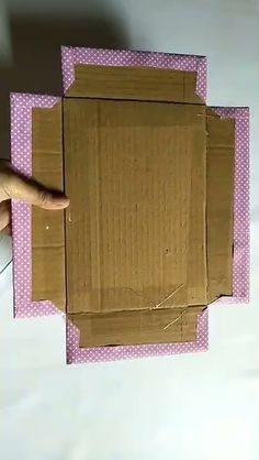 a person is holding up a cardboard box with holes in it and the bottom half has been cut out