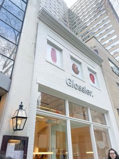 a woman standing in front of a store window with the words glosser on it