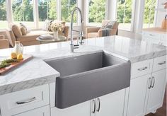 a kitchen with white cabinets and marble counter tops, along with an island in the middle