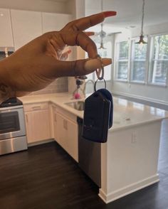 a hand is holding a car key in a kitchen with an island and stove top