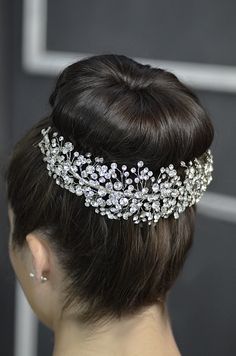 a woman wearing a bridal headpiece with crystal stones and pearls on her hair