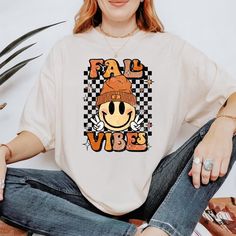 *If you would like a colour or size that is not listed, please contact us. Embrace the cozy autumn season with our Fall Vibes Shirt, designed to bring warmth and style to your wardrobe. Perfect for pumpkin spice lovers and fall enthusiasts. 🍂 Soft and Comfortable: Made from high-quality cotton for a cozy feel, ideal for layering on chilly days. 🎃 Cute Fall Design: Features a retro-inspired graphic that celebrates the beauty of fall, from pumpkins to autumn leaves. 🍁 Versatile Style: Perfect f White Tops For Fan Merchandise In Fall, White Tops For Fall Fan Merchandise, Fall Fan Apparel T-shirt With Graphic Print, Fan Apparel Graphic T-shirt For Fall, Fan Apparel Graphic Print T-shirt For Fall, Fall Graphic Tee Fan Merchandise Tops, Fall Graphic Tee For Fan Merchandise, Fan Merchandise T-shirt For Fall, Retro Fall Tops For Fan Merchandise