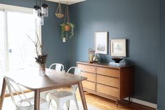 a dining room with blue walls and white chairs