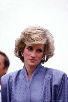 the princess of wales is wearing a blue dress and standing in front of two men