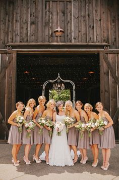 a group of women standing next to each other in front of a barn