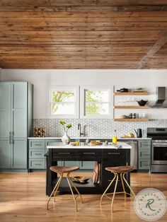 a kitchen with two stools in front of an island and wooden ceiling beams above it