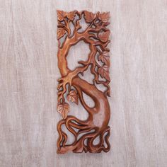 a decorative wooden wall hanging with a tree on it's side and leaves in the middle