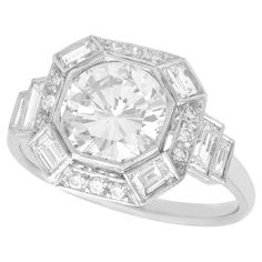 A stunning, fine and impressive contemporary 2.58 carat diamond and platinum Art Deco style dress ring; part of our diverse diamond jewelry collections. This stunning, fine and impressive Art Deco style diamond ring has been crafted in platinum. The millegrain ornamented setting features a 1.90 Ct modern brilliant round cut diamond collet set to the centre of a halo ring design. The halo style border is embellished with twelve claw set modern brilliant round cut diamonds, accented with a baguette cut diamond to each corner. Each of the ring shoulders are embellished with two collet set baguette cut diamonds, graduating in size. This impressive engagement ring has been independently tested using state of the art technology (Niton XL2 Analyzer) and verified as platinum. The ring is supplied Engagement Ring Art Deco, Antique Silver Jewelry, Platinum Engagement Ring, Dress Ring, Contemporary Ring, Art Deco Stil, Estilo Art Deco, Diamond Cocktail Rings, Ring Art Deco