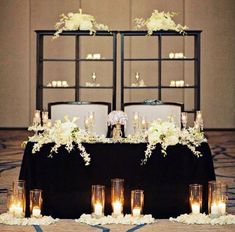 the wedding table is set up with candles and flowers on it, as well as an arrangement