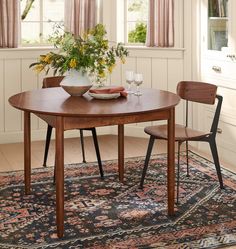 a dining room table with two chairs and a bowl of flowers