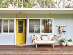 a white couch sitting on top of a wooden floor next to a yellow front door