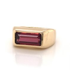 This sleek and modern cocktail ring features a 2.94 carat red garnet in high polished 14 karat yellow gold. The scintillating garnet has a rich pinot noir hue and is bezel set at the face of the ring. The fashionable band features an angular and boxy profile that reaches nearly 5mm above the finger. From the secure gemstone setting to the crisp design, this one of a kind right hand ring is a modern treasure! Classic Formal Burgundy Rings, Modern Ruby Ring For Formal Occasions, Classic Burgundy Ruby Ring For Formal Occasions, Modern Yellow Gold Ruby Ring With Polished Finish, Modern Ruby Ring With Bezel Setting For Formal Occasions, Modern Yellow Gold Ruby Ring For Formal Events, Modern Yellow Gold Ruby Ring For Formal Occasions, Modern Ruby Ring With Polished Finish In 14k Gold, Modern 14k Gold Ruby Ring With Polished Finish