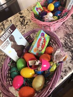 two baskets filled with candy and eggs on top of a counter