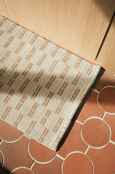 an orange and white rug sitting on top of a floor next to a wooden cabinet