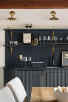 a dining room table with plates and glasses on it, next to an open shelving unit