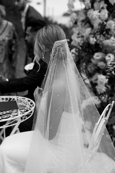 a woman in a wedding dress sitting at a table with a veil on her head