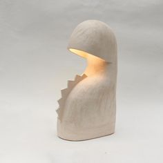 a white ceramic sculpture with a light coming out of it's mouth, on a white background