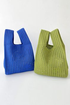 two purses sitting next to each other on a white surface, one in blue and the other in green