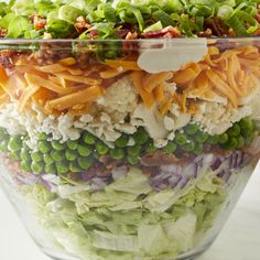 a salad in a glass bowl with carrots, lettuce and other vegetables