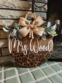 a wooden sign that says mr and mrs wood with a bow on the front, sitting next to a fireplace