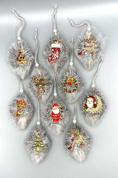 twelve glass christmas ornaments with santa hats, stockings and snowflakes hanging from strings