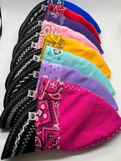 a row of different colored bandanas sitting on top of a white table next to each other