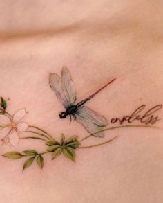 a woman's chest with a dragonfly on it and flowers in the foreground