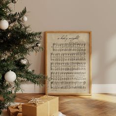 a christmas tree with presents under it in front of a sheet music print on the wall