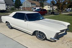 an old white car is parked on the sidewalk