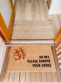 a pair of sandals sitting on the floor next to a door mat that says oh hey, please remove your shoes