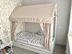 a bed with a canopy over it in a room next to a book shelf and bookshelf