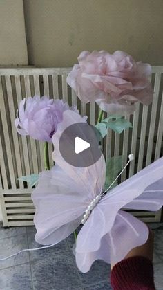 a person is holding some paper flowers in their hand and there is a butterfly on top of the flower